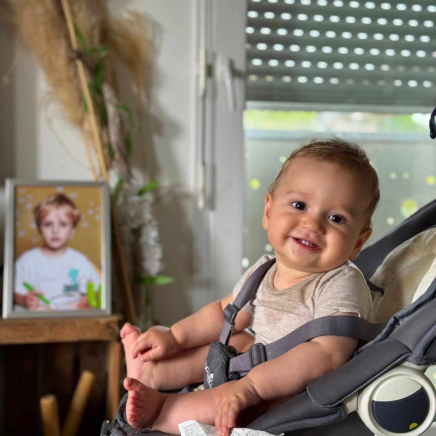 Luken participe au concours pour gagner de l'argent avec cette photo : baby, blurred_background, child, clothing, face, furniture, happy, home, houseplant, indoor, infant, light, paper, photograph, portrait, seat, smile, stroller, toy, window