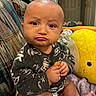 baby, blanket, child, clothing, comfort, couch, cute, expression, face, foot, furniture, hand, home, indoor, pattern, plush_toy, portrait, pout, seated, snack