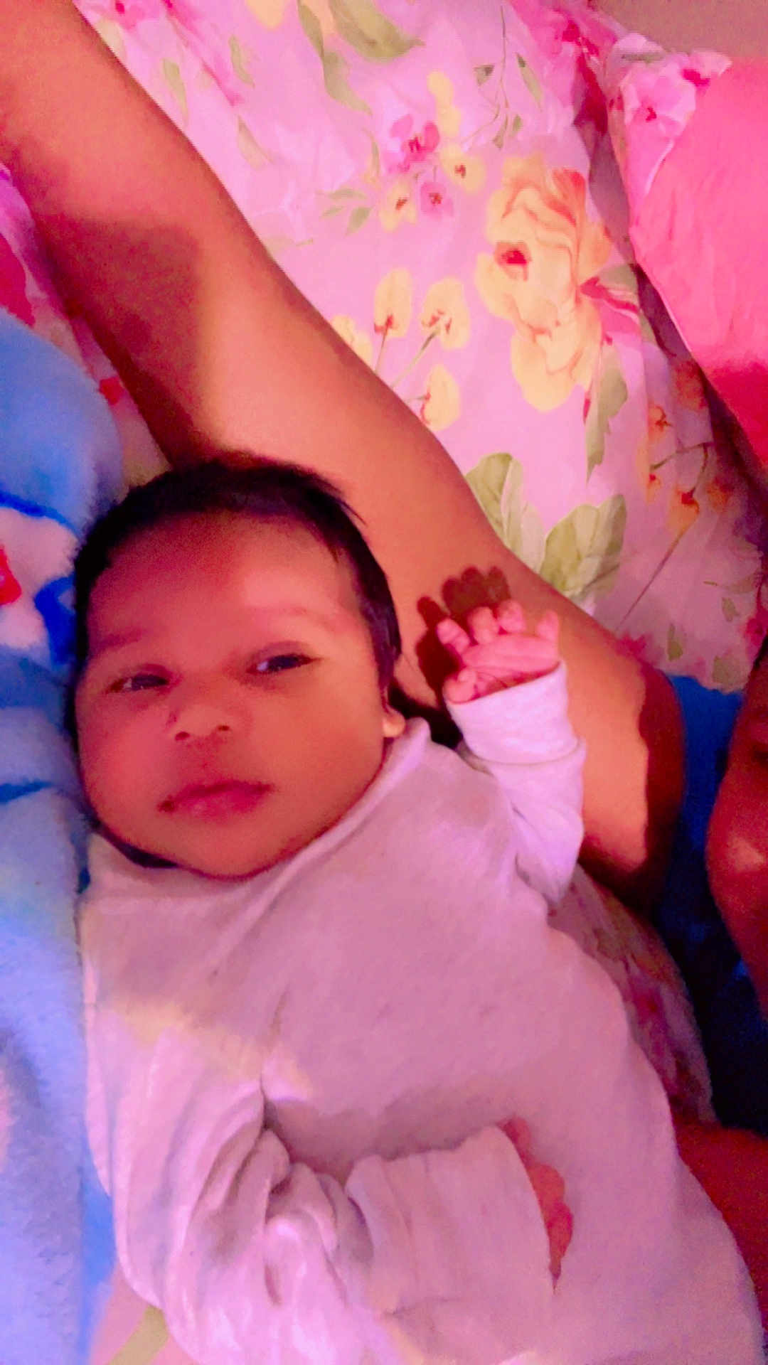 Joshua Pavon is registered to the contest to win money with this photo: baby, infant, blanket, bed, floral_bedspread, person, hand, sleepwear, lying_down, soft_toys, comfort, cute, newborn, indoors, portrait, child, warm_colors, resting, family, cozy