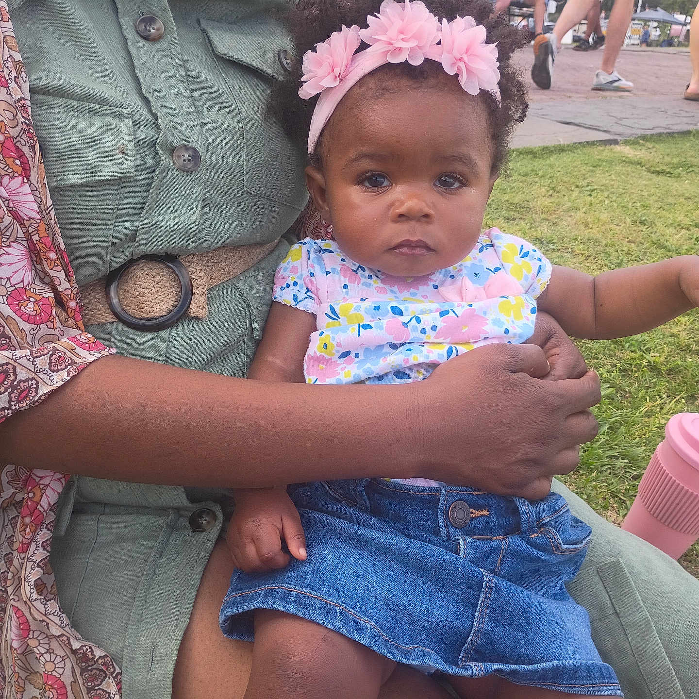 Yalonda is registered to the contest to win money with this photo: adult, baby, casual_clothing, child, colorful_clothing, cup, denim_skirt, flower_headband, grass, hand, headwear, lap, outdoor, park, people, pink, portrait, sitting, summer, walking