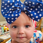 Prudence is registered to the contest to win money with this photo: baby, blue_bow, chair, child, closeup, clothing, curious, cute, expression, face, headband, indoor, patterned_clothing, person, portrait, red_white_blue, star_pattern, table, toddler, young_child
