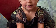 Raylynn joined the competition — help win amazing prizes! toddler, child, dress, black_dress, flower_accessories, pink_flowers, couch, red_couch, cat, lamp, chevron_lamp, pillow, floral_pattern, indoor, cute, smiling, sitting, hands, bracelet, home