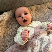 Josephine joined the competition — help win amazing prizes! baby, infant, face, expression, blanket, cozy, hand, wide_eyes, mouth_open, lying_down, cute, child, soft_texture, warm, indoor, person, young, portrait, skin, clothing