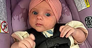 Josephine is registered to the contest to win money with this photo: baby, car_seat, child, closeup, clothing, cute, flower, hand, headband, indoor, infant, looking, pink, portrait, purple, safety, seat, straps, warning_labels, wide_eyes