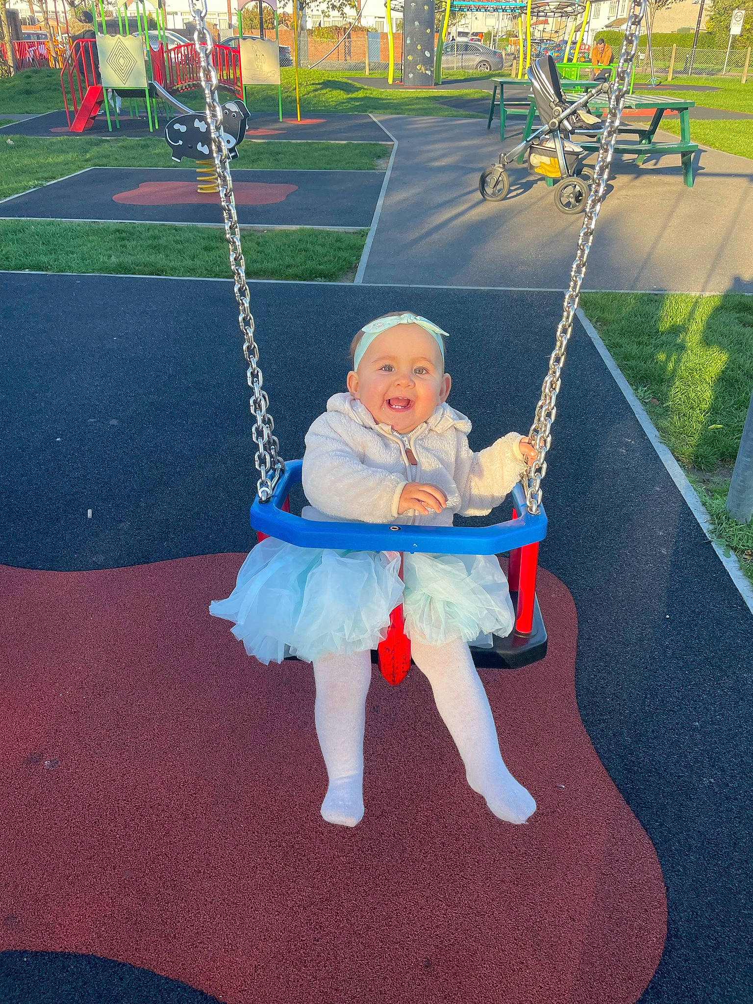 Bonnie is registered to the contest to win money with this photo: baby, child, city, electric_blue, fun, grass, happy, headwear, joy, leisure, outdoor_play_equipment, person, plant, play, playground, pole, recreation, sitting, swing, toddler