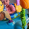 Tirzah joined the competition — help win amazing prizes! baby, child, infant, smiling, sitting, activity_center, play_gym, toy, colorful, pink_clothing, bottle, feeding, indoor, portrait, face, eyes, curly_hair, plastic_toys, blue_seat, carpet
