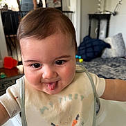 Spencer joined the competition — help win amazing prizes! baby, child, tongue_out, bib, easter, indoor, smiling, person, cute, face, head, clothing, playful, home, furniture, carpet, pillow, toy, table, living_room