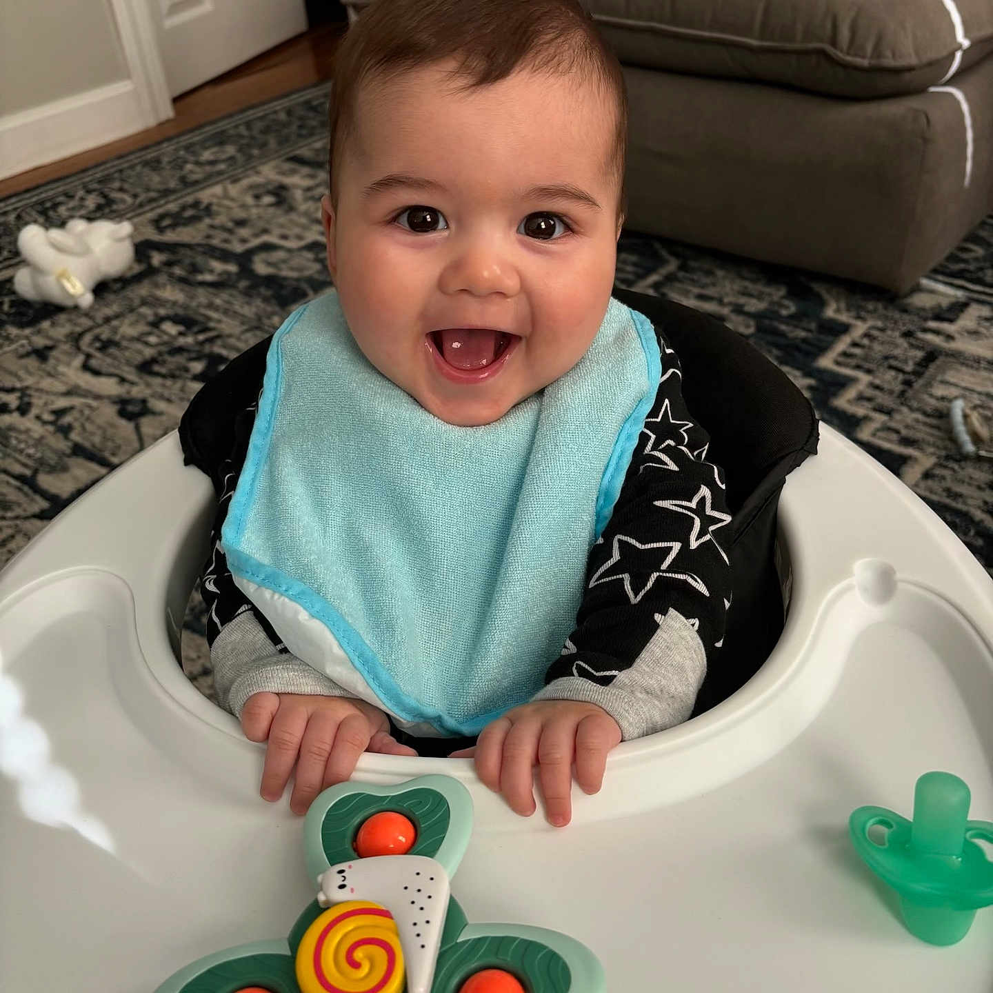 Spencer joined the competition — help win amazing prizes! baby, baby_walker, bib, black_hair, carpet, child, clothing, couch, face, furniture, hands, happy, indoor, infant, living_room, pacifier, plush_toy, portrait, smiling, toy