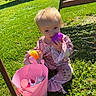 toddler, child, pink_pajamas, toy, bucket, grass, outdoor, sunny, playing, baby, purple_toy, yellow_toy, green_grass, cute, sitting, daylight, face, person, happy, playtime