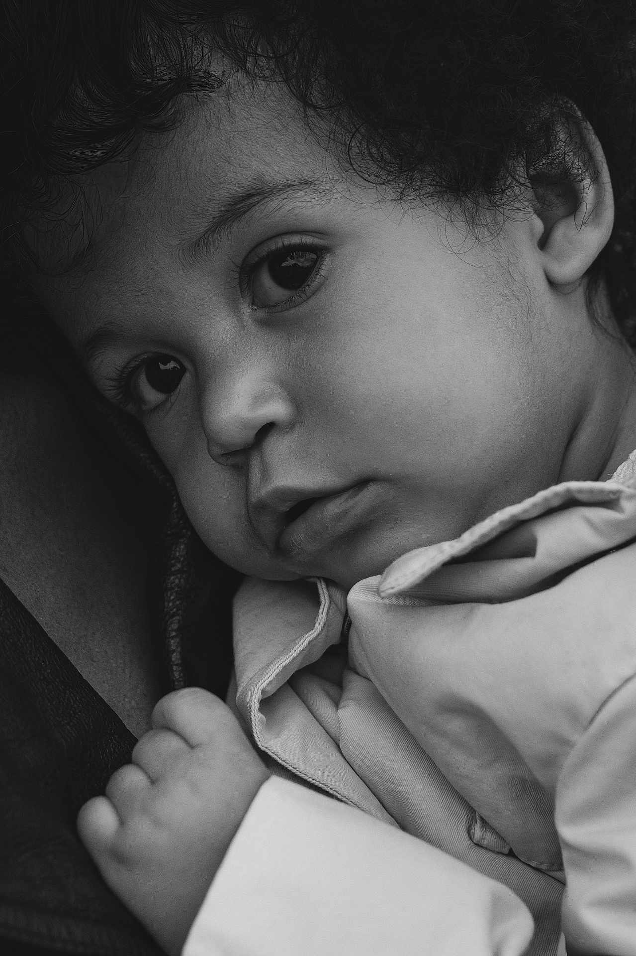 Yekaterina is registered to the contest to win money with this photo: child, toddler, infant, portrait, close_up, black_and_white, monochrome, face, eyes, curly_hair, hand, ear, jacket, clothing, soft_lighting, intimate, sleepy, emotive, skin_texture, portrait_photography