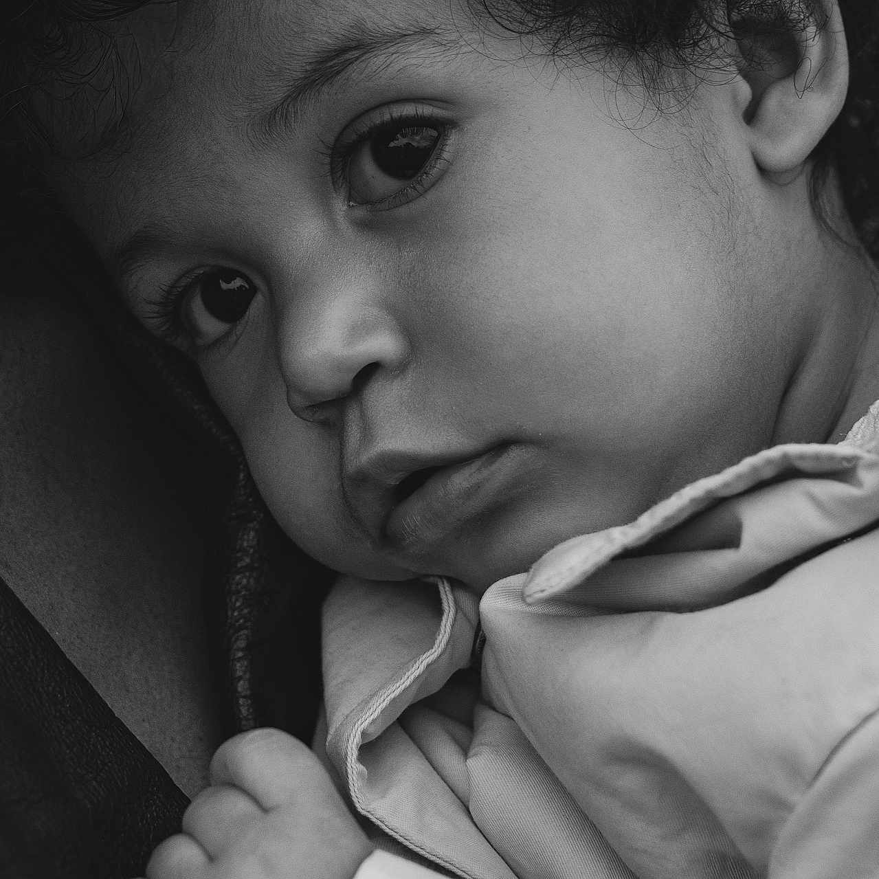 Luba is registered to the contest to win money with this photo: baby, black_and_white, candid, child, close_up, clothing, curly_hair, emotion, expression, face, hand, innocence, intimate, monochrome, portrait, resting, skin, soft_light, texture, young