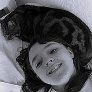 Larry a rejoint le concours — aidez-le/la à gagner de superbes lots ! child, smile, face, cat, pet, lying_down, bed, blanket, hair, indoor, animal, feline, resting, cozy, black_and_white, portrait, happy, young, relaxing, closeup