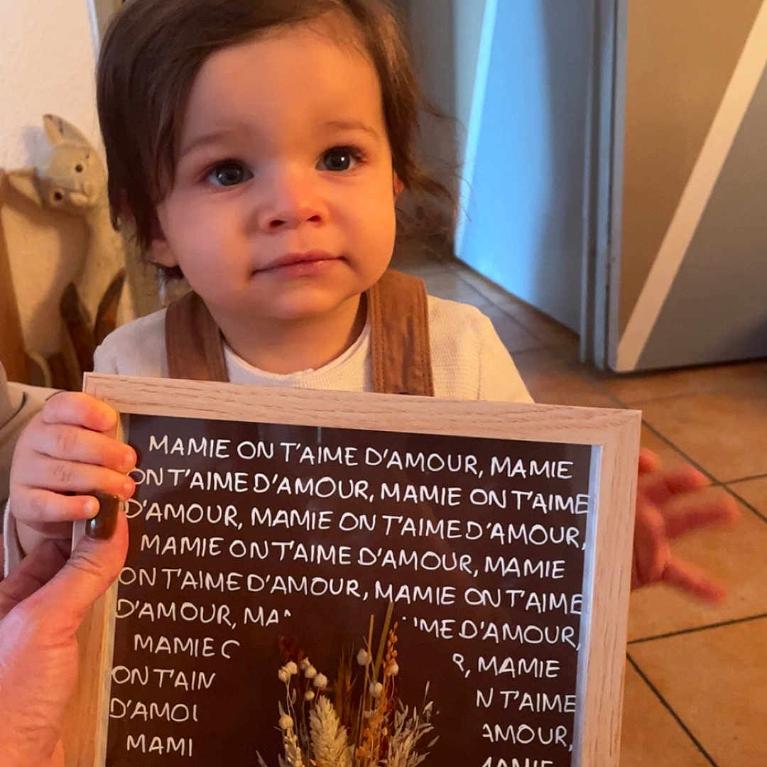 Isaac participe au concours pour gagner de l'argent avec cette photo : adult, baby, blackboard, bodypart, face, female, finger, flower, flowerarrangement, hand, hardwood, head, person, photography, plant, plywood, portrait, text, woman, wood