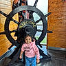 Janelle is registered to the contest to win money with this photo: child, girl, hoodie, pink, jeans, heart_pattern, shoes, pink_shoes, pirate_statue, ship_wheel, welcome_sign, wooden_wall, graffiti, indoor, floor_tiles, smiling, cute, posing, casual_clothing, statue