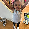 Janelle joined the competition — help win amazing prizes! toddler, child, indoor, wooden_floor, staircase, toy_shopping_cart, pink_headband, flower, grey_shoes, white_sneakers, black_leggings, grey_tank_top, happy, smiling, arms_up, person, floor, home, play, casual_clothing