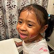 Janelle is registered to the contest to win money with this photo: child, girl, smiling, face_paint, necklace, white_shirt, messy, bathroom, sink, curtain, floral_pattern, hair_tied, earrings, standing, playful, indoors, portrait, young, cute, happy