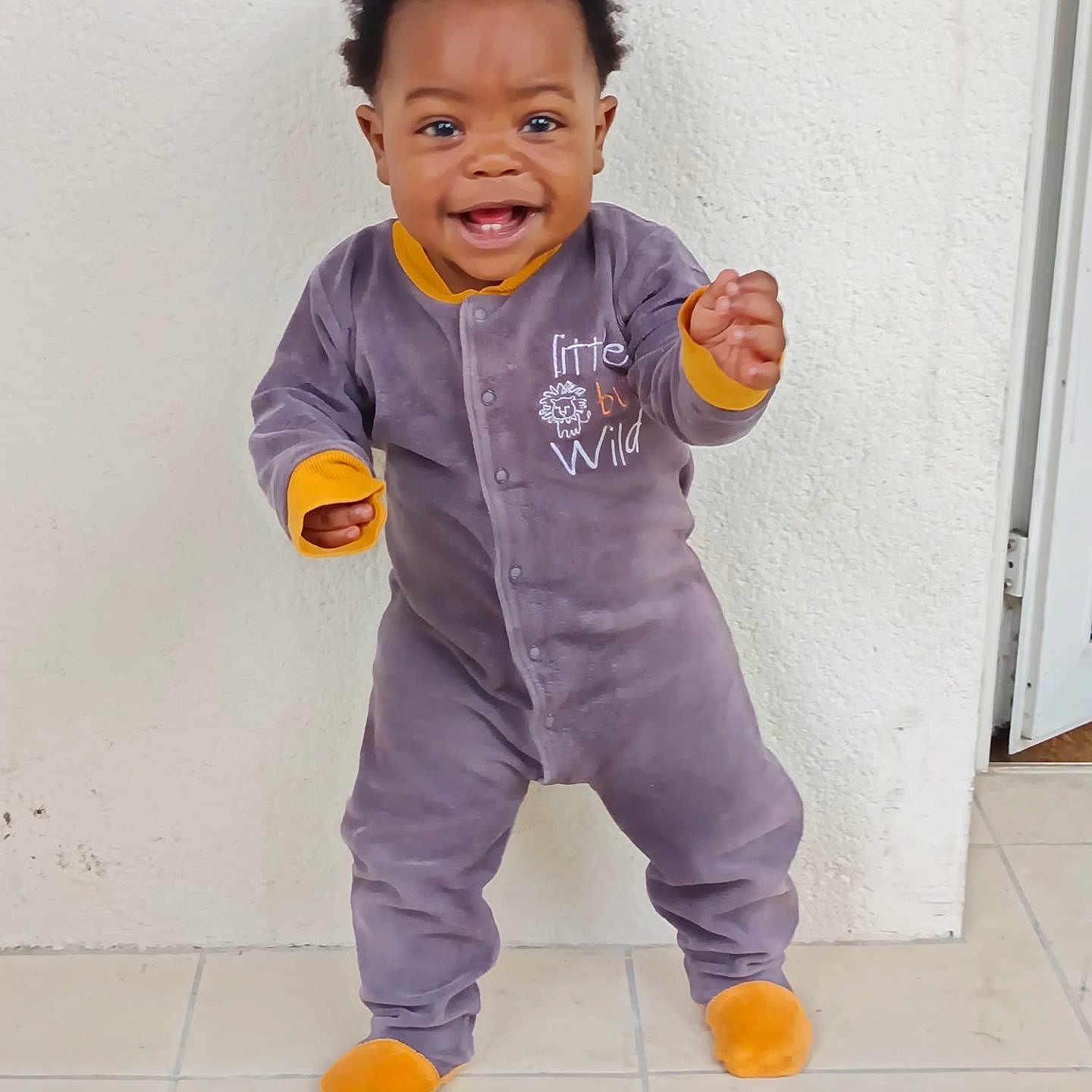 Ravi Manuel participe au concours pour gagner de l'argent avec cette photo : baby, child, clothing, cute, expression, face, floor, footwear, happy, indoor, infant, onesie, person, playful, portrait, smiling, standing, tile, wall, young