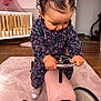 baby, carpet, child, clothing, crib, curly_hair, cute, focused, furniture, grip, hair_clips, handlebars, indoor, nursery, pink, play, shoes, toddler, toy_car, wooden_floor