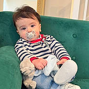 Oliver is registered to the contest to win money with this photo: baby, blue_jeans, casual_clothing, child, cozy, curious, cute, green_couch, home_interior, indoor, infant, pacifier, portrait, relaxed, seated, soft_toy, striped_sweater, stuffed_animal, white_shoes, young_child