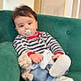 baby, blue_jeans, casual_clothing, child, cozy, curious, cute, green_couch, home_interior, indoor, infant, pacifier, portrait, relaxed, seated, soft_toy, striped_sweater, stuffed_animal, white_shoes, young_child