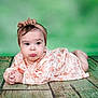 Roukaya participe au concours pour gagner de l'argent avec cette photo : baby, child, infant, pout, drool, headband, floral_dress, lying_down, wooden_floor, green_background, portrait, cute, expression, hands_clasped, indoors, young_child, face, skin, person, adorable