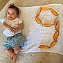 baby, child, cantaloupe, fruit, number, carpet, cloth, smiling, infant, casual_clothing, shorts, tshirt, laying_down, indoor, healthy_food, orange, fresh, cute, relaxed, playful