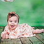 Roukaya a rejoint le concours — aidez-le/la à gagner de superbes lots ! baby, child, smiling, headband, dress, lying_down, wooden_floor, green_background, happy, cute, portrait, infant, hands, face, eyes, skin, young, one_person, indoors, clothing