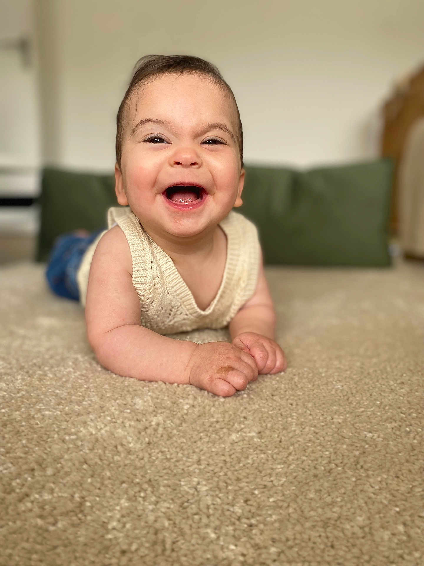 Roukaya participe au concours pour gagner de l'argent avec cette photo : baby, smiling, carpet, indoor, child, knitwear, sleeveless, happy, face, person, cushion, green, blue_pants, cute, infant, portrait, young_child, lying_down, home, cozy