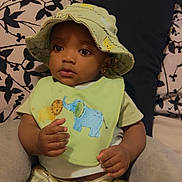 Namari is registered to the contest to win money with this photo: baby, child, hat, bib, animal_design, plush_toy, bed, pillow, patterned_bedding, clothing, shorts, sitting, indoors, cute, small_hands, face, eyes, portrait, soft_toy, infant