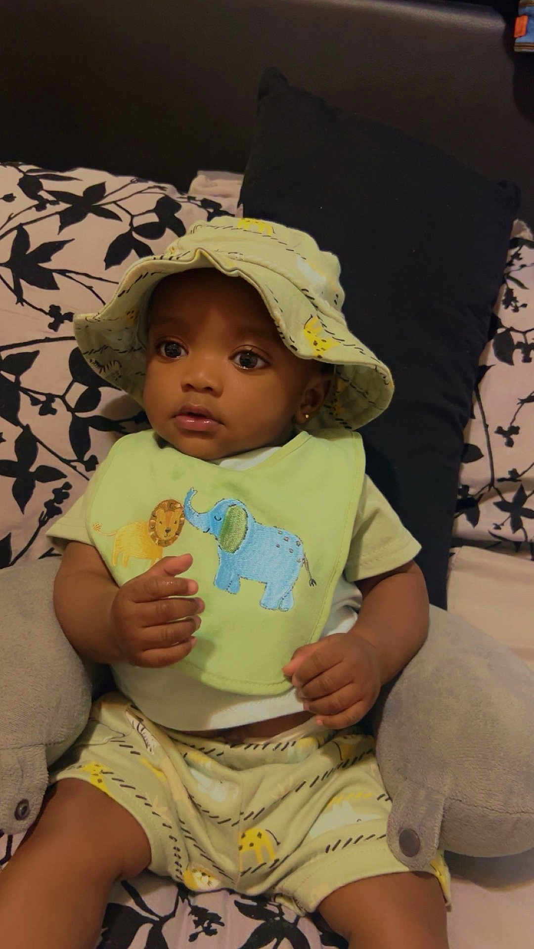 Namari is registered to the contest to win money with this photo: baby, child, hat, bib, animal_design, plush_toy, bed, pillow, patterned_bedding, clothing, shorts, sitting, indoors, cute, small_hands, face, eyes, portrait, soft_toy, infant