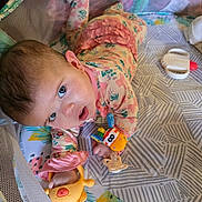 Emberly joined the competition — help win amazing prizes! baby, infant, child, playpen, toy, pajamas, patterned_mat, mesh, colorful, cute, lying_down, hand, face, blue_eyes, expression, indoors, playtime, soft_toys, floral_clothing, curious