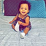 Arayah is registered to the contest to win money with this photo: toddler, child, smiling, bed, pillow, dress, socks, curly_hair, indoor, happy, person, home, furniture, headboard, fabric, pattern, cute, sitting, young_child, playful