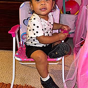 Arayah joined the competition — help win amazing prizes! toddler, child, polka_dot, shirt, black_shorts, black_shoes, white_socks, chair, pink_chair, carpet, curly_hair, indoor, toy, dresser, person, cute, curious, room, furniture, playful