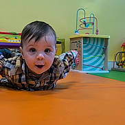 Guerlin a rejoint le concours — aidez-le/la à gagner de superbes lots ! toddler, child, playroom, toy, orange_mat, curious, wide_eyes, plaid_shirt, indoor, floor, colorful, green_wall, play, baby, expression, arms_outstretched, young_child, head, smile, person