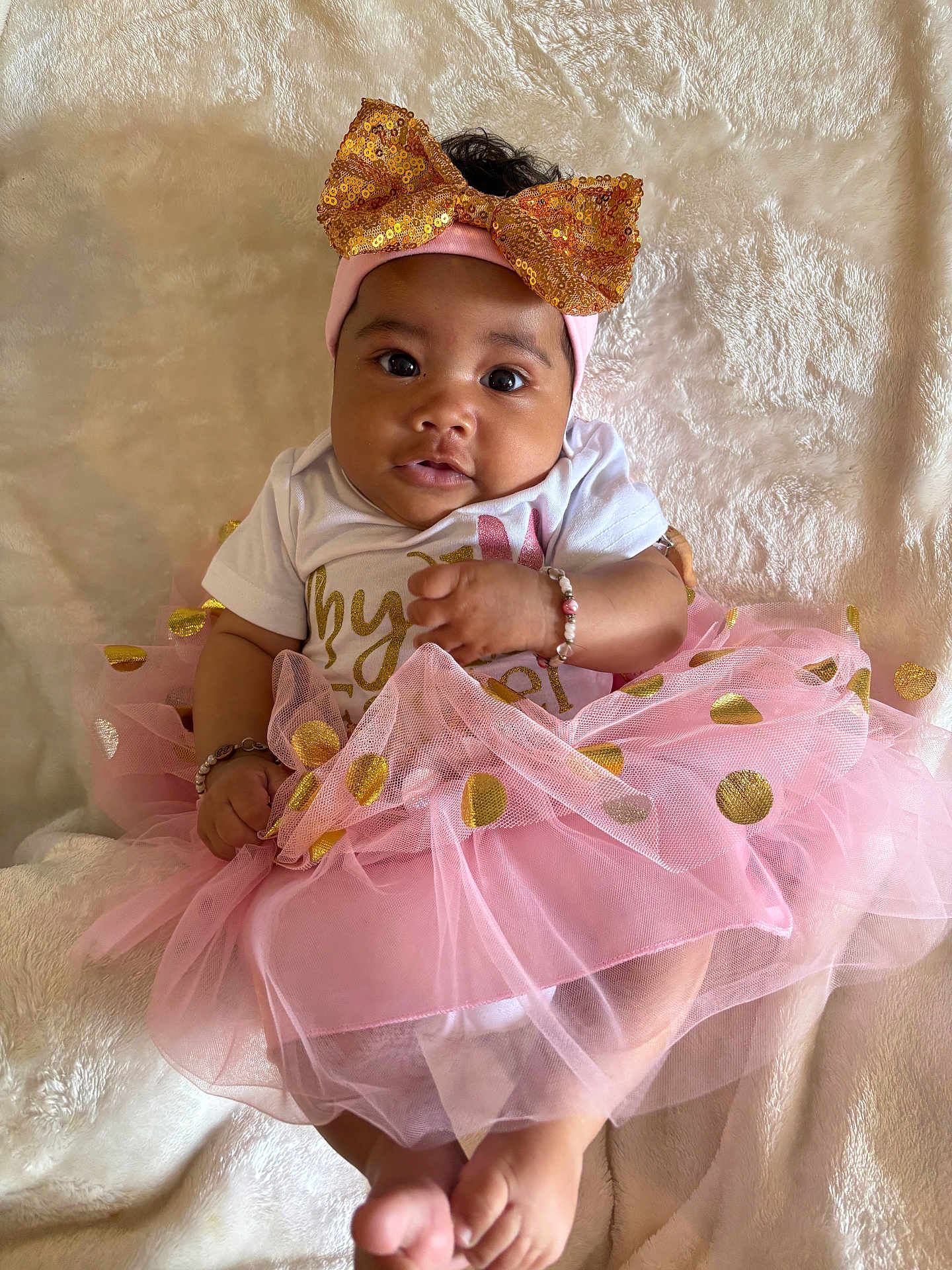 Dutchess joined the competition — help win amazing prizes! baby, infant, tutu, pink, gold, headband, bow, bracelet, white_blanket, cute, child, portrait, sitting, clothing, soft_texture, happy, hands, feet, face, indoors