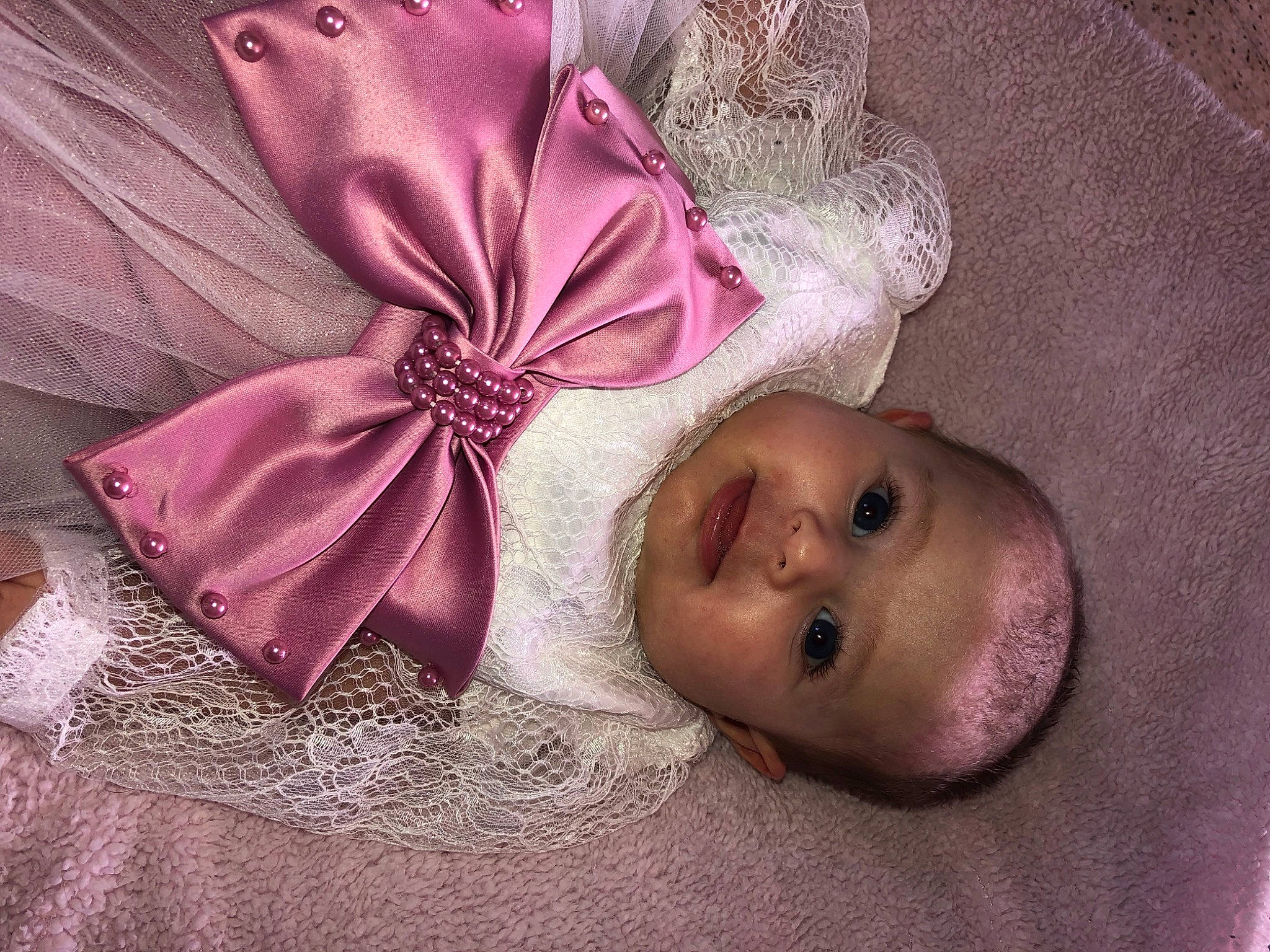 Mélina a rejoint le concours — aidez-le/la à gagner de superbes lots ! baby, baby_toddler_clothing, bridal_accessory, child, costume_hat, face, fashion_accessory, hair_accessory, headgear, headpiece, linens, magenta, person, petal, pink, purple, ribbon, satin, smile, tie