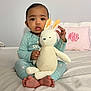 baby, child, plush_toy, bunny, pajamas, bed, pillow, foot, hand, face, indoors, cute, soft_toy, person, sleepwear, infant, monogram, comfort, toy, cozy