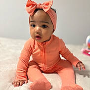 Mylani joined the competition — help win amazing prizes! baby, infant, child, headband, bow, peach_color, pajamas, ribbed_fabric, sitting, soft_surface, curious, cute, indoors, portrait, person, small_hands, footed_pajamas, expression, young_child, cozy