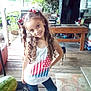 child, girl, curly_hair, hair_bows, tank_top, american_flag, porch, wooden_floor, dog, watermelon, table, outdoor, smile, happy, casual_clothing, toy, plants, chair, household_items, daylight