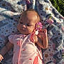 baby, infant, blanket, pink_clothing, butterfly, flower, grass, outdoor, child, nature, cute, soft_texture, sunlight, peaceful, lying_down, small_hand, head, face, portrait, relaxation