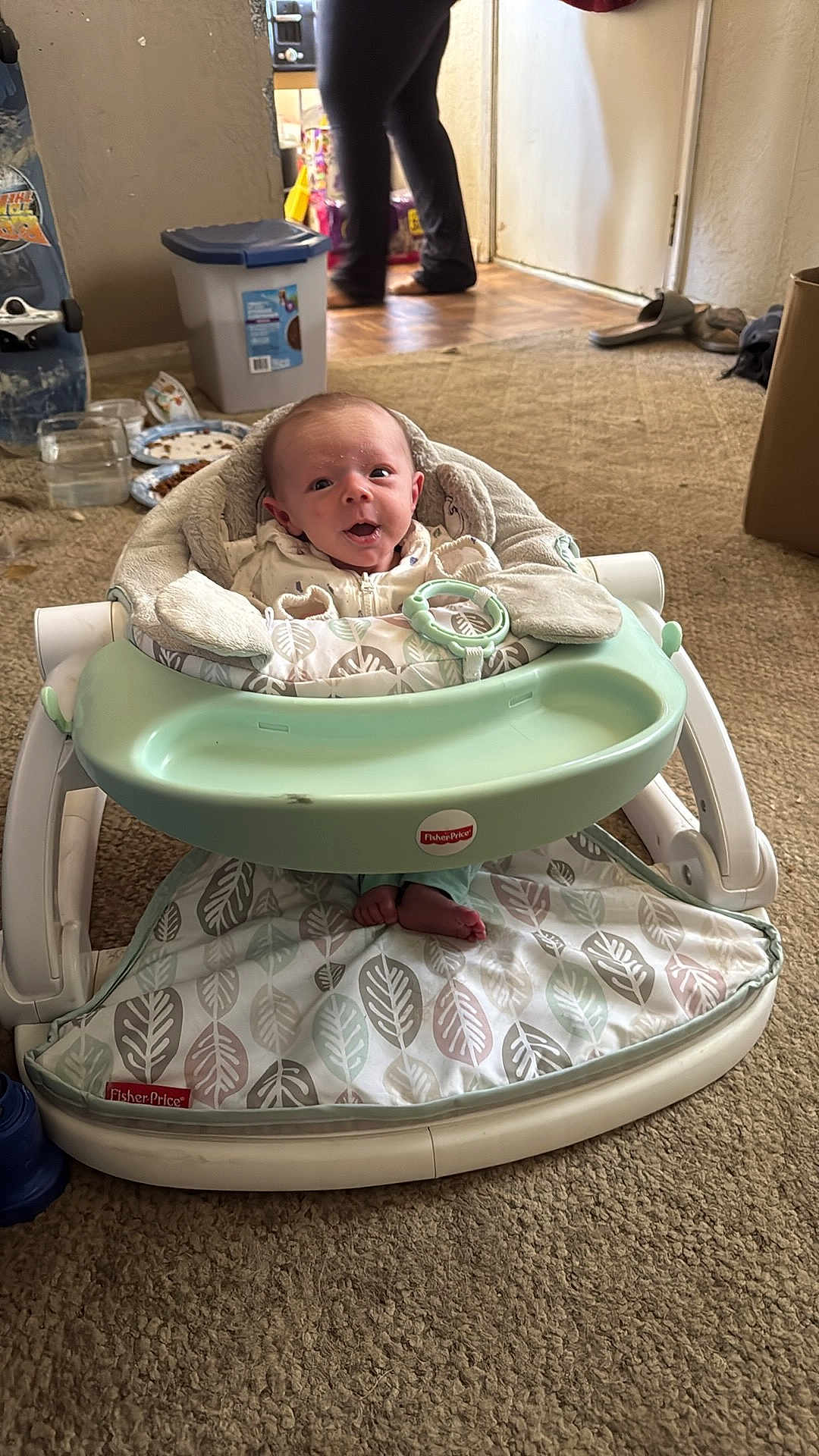 Aviya is registered to the contest to win money with this photo: baby, infant, baby_seat, fisher_price, carpet, indoor, person, footwear, toy, blanket, floor, expression, head, face, clothing, adult, legs, container, household_items, door