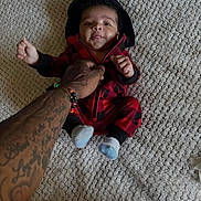 Kealo joined the competition — help win amazing prizes! baby, infant, child, carpet, tattoo, hand, socks, hoodie, red_clothing, black_clothing, person, cute, smile, tongue_out, indoor, floor, texture, human, young_child, holding