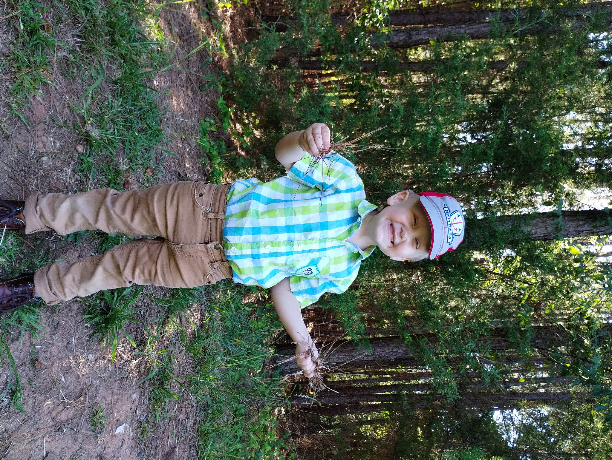 Tyler is registered to the contest to win money with this photo: baby_laughing, baby_toddler_clothing, child, fun, grass, happy, hat, headwear, joy, leisure, people_in_nature, person, plant, play, smile, soil, t_shirt, toddler, tree, water
