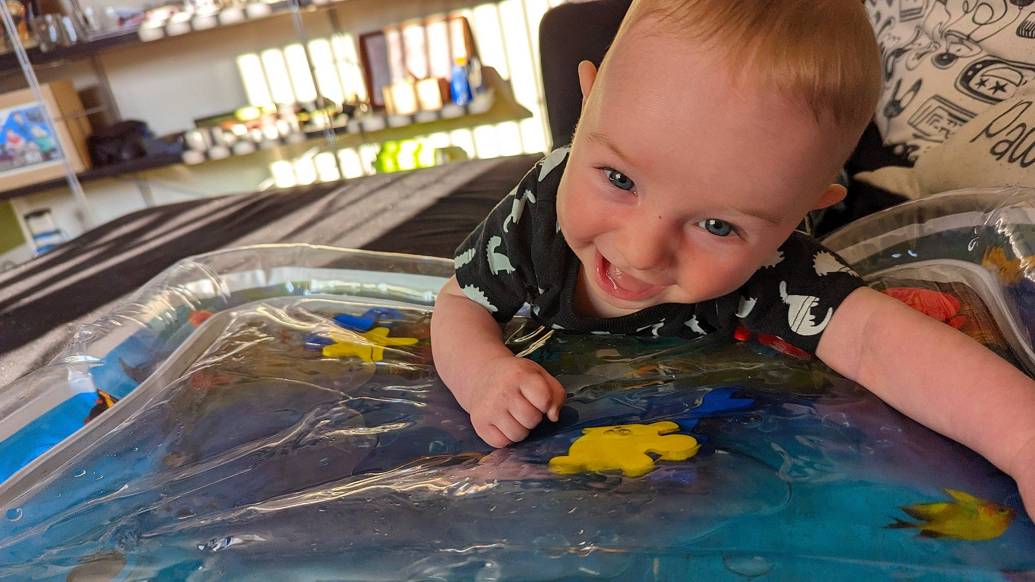 Ethan is registered to the contest to win money with this photo: baby, baby_products, baby_toddler_clothing, cheek, child, facial_expression, flooring, fun, happy, iris, leisure, person, plastic, play, recreation, sitting, smile, toddler, toy, toy_vehicle