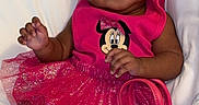 Amira is registered to the contest to win money with this photo: baby, infant, child, portrait, sitting, lying_down, smiling, pink_outfit, dress, skirt, hair_bow, headband, handbag, minnie_mouse, sparkles, socks, bed, bedding, indoors, fashion