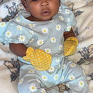 Amira is registered to the contest to win money with this photo: baby, infant, child, portrait, smiling, wide_eyed, indoor, blanket, bed, bow, headband, daisy_print, yellow_mittens, onesie, baby_clothing, sitting, lying_down, cozy, close_up, photography
