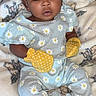 baby, infant, child, portrait, smiling, wide_eyed, indoor, blanket, bed, bow, headband, daisy_print, yellow_mittens, onesie, baby_clothing, sitting, lying_down, cozy, close_up, photography