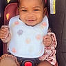 Amira joined the competition — help win amazing prizes! baby, infant, child, smiling, portrait, car_seat, seatbelt, bow_headband, bib, floral_clothing, patterned_clothing, baby_socks, sitting, indoor, vehicle, sunlight, happy, face, safe, close_up