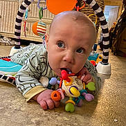 Leon is registered to the contest to win money with this photo: baby, infant, toy, floor, indoor, child, play, colorful, curious, face, hand, clothing, baby_gym, head, mouth, looking, expression, crawling, room, carpet