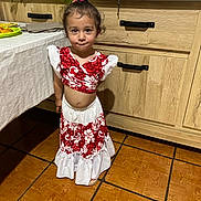 Eléyana a rejoint le concours — aidez-le/la à gagner de superbes lots ! cabinet, casual, child, curly_hair, face, floor, food, girl, indoor, kitchen, person, portrait, red_clothing, smile, standing, table, tile_floor, white_clothing, wooden_furniture, young_child